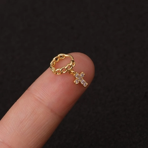 Λήψη macro από χρυσό σκουλαρίκι ear cuff με σταυρό από ζιργκόν φορεμένο στο δάχτυλο