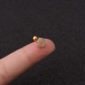 Dettaglio dell'orecchino a vite in oro con zirconi tenuto tra la punta delle dita