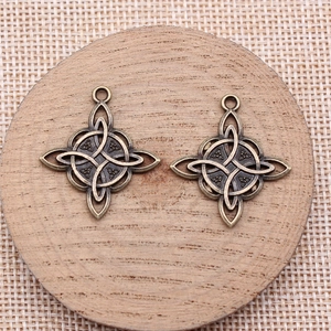 Pair of antique bronze Celtic knot cross pendants on a rustic wooden base for DIY jewelry