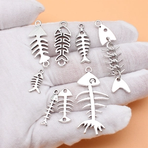 Set of 8 vintage silver fishbone pendants for DIY jewelry making held in palm
