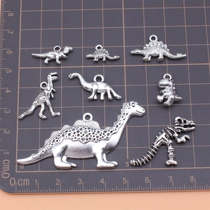 Set mit 8 antik-silbernen Dinosaurier-Anhängern aus Legierung auf einem Maßstab-Gitter