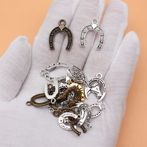 Set of lucky horseshoe charms in mixed metal colors held in hand for size reference