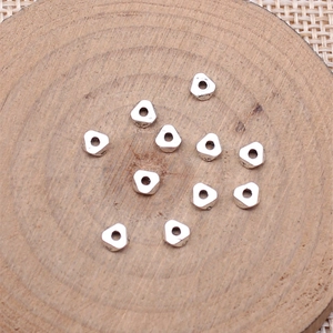Silver triangle spacer beads for DIY jewelry making on a minimalist wood texture base