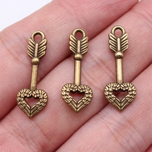 Three vintage heart arrow charms in antique bronze finish displayed on a hand palm