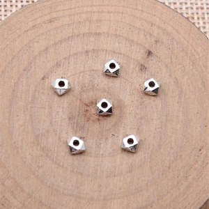 Geometrische facettierte Silber-Metallperlen auf Holztablett für DIY-Schmuck