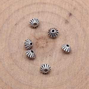 Vintage silver cone spacer beads with radial engraving on rustic wood background