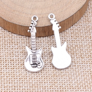 Antique silver bass guitar alloy pendants showing front and back detail on a woven surface