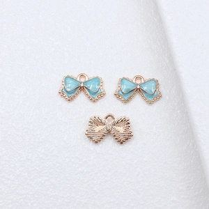 Front and back views of 10x16mm light blue enamel bow pendants with gold metal trim