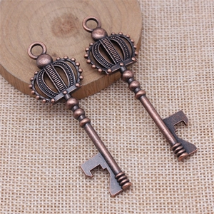 Antique copper crown key bottle opener pendant on a rustic wooden and woven background
