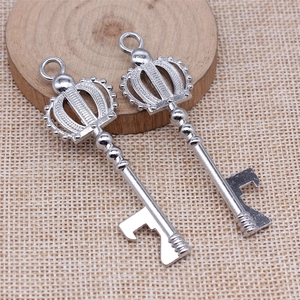 Silver crown key bottle opener pendant set on a rustic wooden base with woven texture