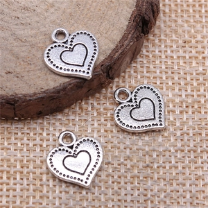Tre ciondoli a cuore in argento vintage per gioielli fai-da-te su sfondo di legno rustico
