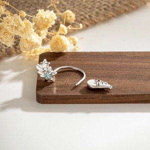 Silver star wing ear cuff with blue square gemstone on rustic wooden display stand