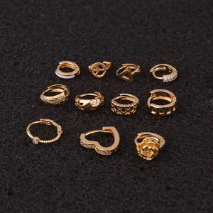 Flat lay of 11-piece golden heart and rose huggie hoop earring set on black foam