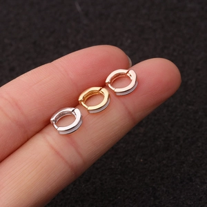 Detailed view of three mini hoop earrings in gold, silver and rose gold finishes on a fingertip