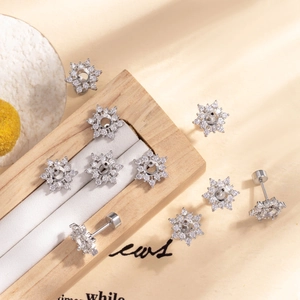 Silver snowflake ear studs with sparkling zircons on a wooden jewelry box backdrop