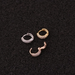 Detailed macro view of heart-shaped zircon hoop earrings in silver, gold, and rose gold