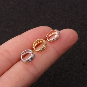 Detailed close-up of three small textured huggie hoop earrings in gold, silver and rose gold