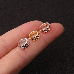 Detailed view of three mini huggie earrings with heart patterns in gold, silver, and rose gold