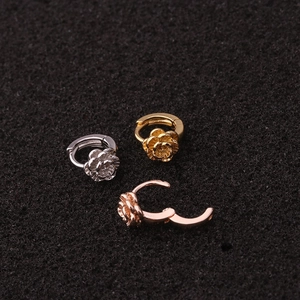 Macro view of three mini rose-shaped huggie earrings in gold, silver, and rose gold