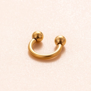 Dettaglio macro di anello a ferro di cavallo dorato con doppie sfere e finitura lucida