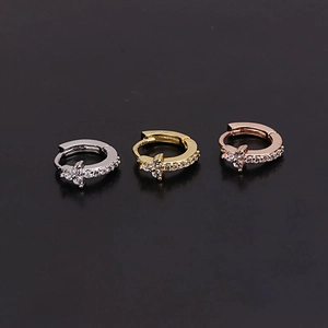Close-up of three mini hoop earrings with zircon flower studs in gold, silver, and rose gold
