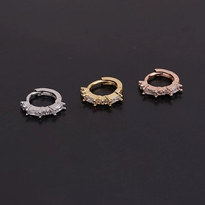 Close-up of gold silver and rose gold huggie earrings set with baguette cut cubic zirconia