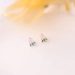Macro shot of colorful peach-shaped stud earrings in gold and silver plating