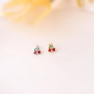Macro detail of cherry zircon stud earrings in silver and gold with screw flat backs