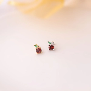 Macro detail of red cubic zirconia apple stud earrings in gold and silver plating