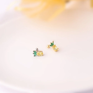 Macro detail of pineapple stud earrings with yellow and green zircons on a clean background