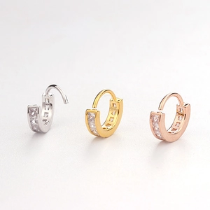 Detail of three hinged hoop earrings in silver, gold, and rose gold with square zircons