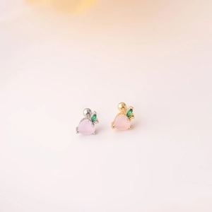 Detail showing gold and silver fruit-shaped screw back earrings with pink gemstones