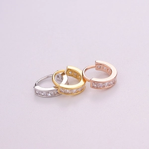 Macro detail of three-piece piercing set with square-cut zircon in gold and silver