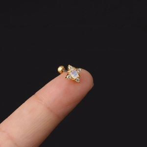 Dettaglio di orecchino 20G in acciaio con pietra ovale e zirconi tenuto sulla punta delle dita