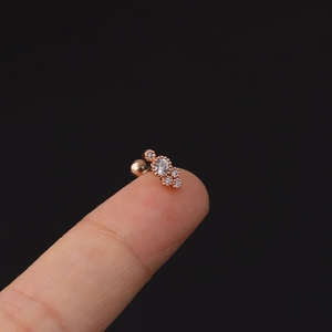 Dettaglio ravvicinato di orecchino in oro rosa con zirconi tenuto sulla punta del dito