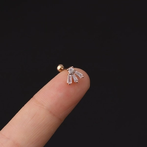 Vista macro di un piccolo piercing in oro rosa con zirconi tenuto sulla punta del dito