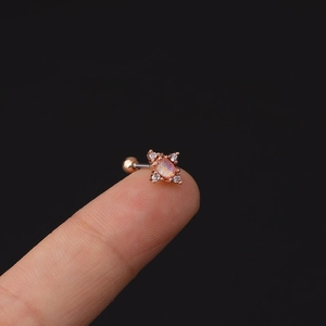 Dettaglio macro di piercing in oro rosa con opale e zirconi sulla punta del dito