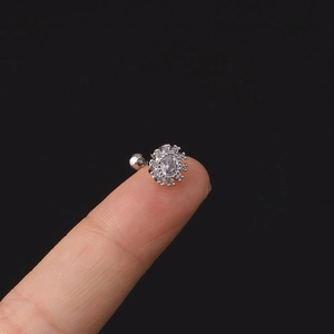 Dettaglio macro di un piccolo orecchino a lobo in acciaio con zircone su un dito