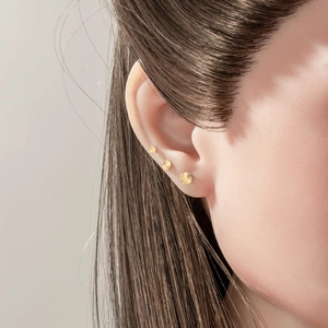 Three-piece gold G23 titanium sunburst stud earrings set worn on ear model