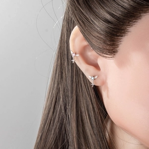 Silver angel wing cross stud earrings with pink and blue stones on female model