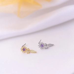 Detailed macro of L-shaped nose studs with star pendant and dangling purple cubic zirconia