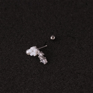 Dettaglio macro di piercing per cartilagine in acciaio con fiori di zircone e perla