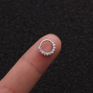Makroaufnahme von versilbertem Nasenring mit Zirkonia auf Fingerspitze zeigt kleine Größe