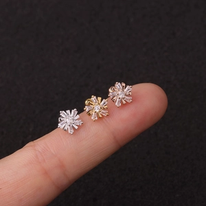 Dettaglio dei tre orecchini a lobo a fiore in zircone in argento, oro e oro rosa