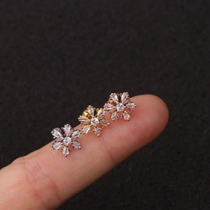 Dettaglio macro degli orecchini a fiocco di neve in argento, oro e oro rosa con zirconi