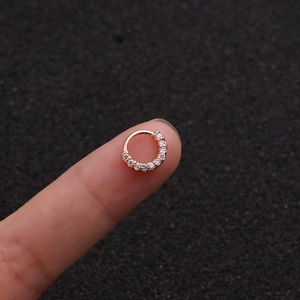 Nahaufnahme eines kleinen roségoldenen Piercing-Rings mit Zirkonia neben einem Finger