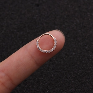 Nahaufnahme eines roségoldenen Piercingrings mit weißen Zirkonia auf der Fingerspitze