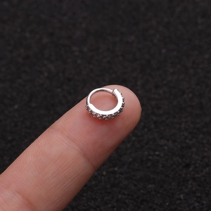 Makroansicht eines silbernen Kupfer-Piercingrings mit Zirkonia auf dunklem Hintergrund