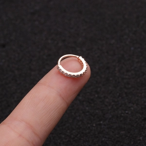 Nahaufnahme von roségoldfarbenem Nasenring mit Zirkon-Steinen auf einer Fingerspitze