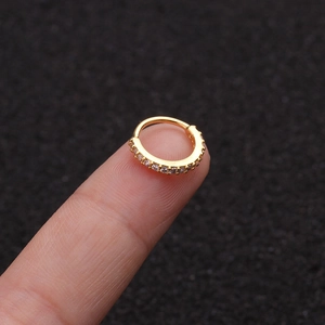 Detail eines vergoldeten Nasenrings mit Zirkonia-Steinen auf der Fingerspitze gezeigt